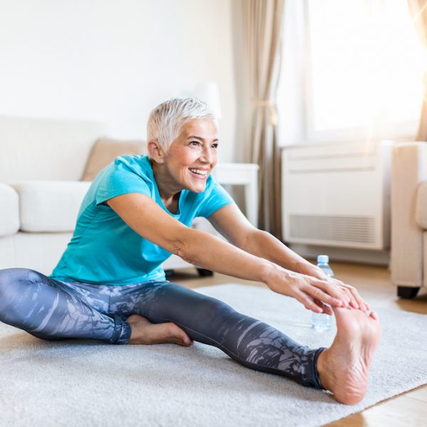 senior woman doing warmup workout at home. Fitness woman doing stretch exercise stretching her legs,quadriceps .Elderly woman living an active lifestyle.
