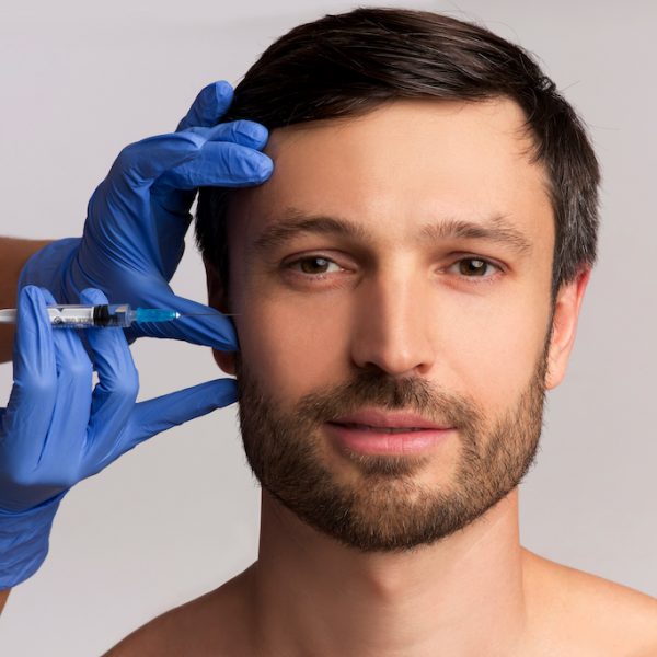 Male Injective Cosmetology. Middle Aged Man Receiving Wrinkle-Removing Injection Over White Studio Background.
